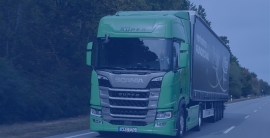 A green truck driving along a highway