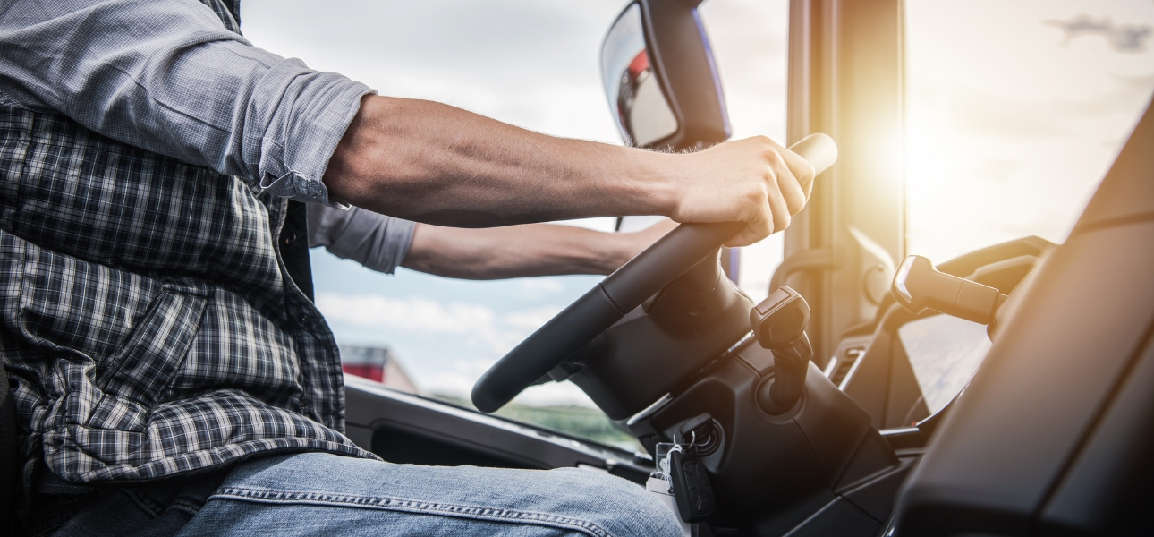 A man driving a truck with sunlight streaming through the window