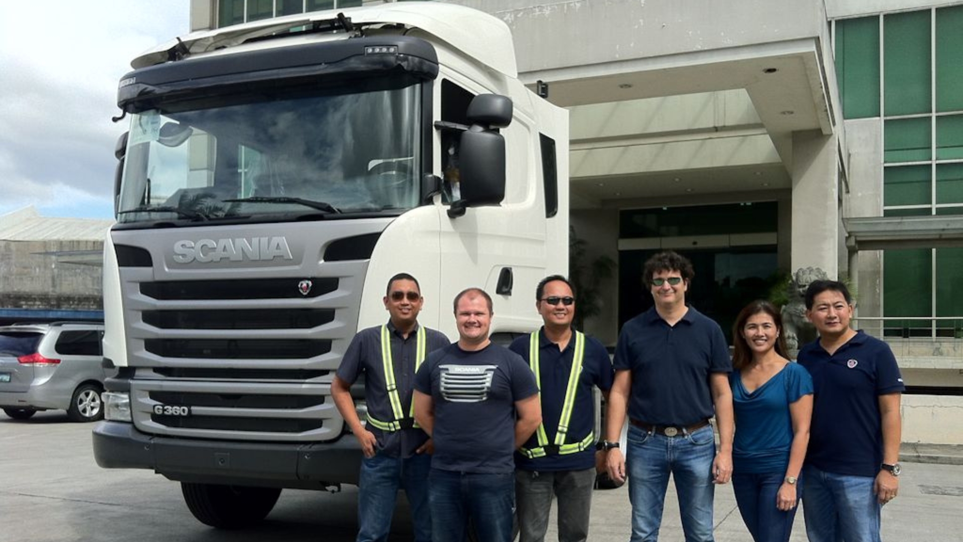 a group of five people stands beside a large truck