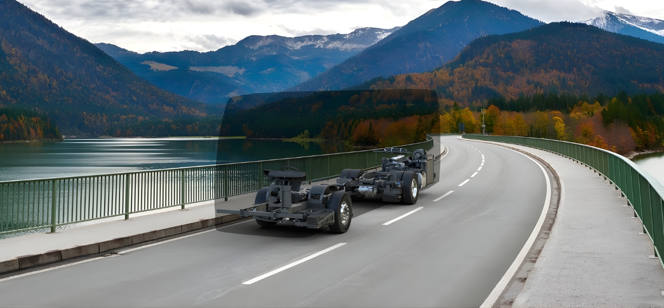 A Scania chassis drives across a bridge spanning a river under a clear blue sky.