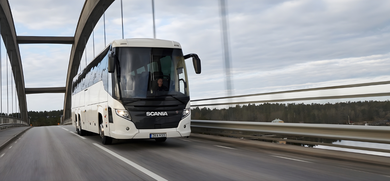 A Scania bus drives along a bridge over a river