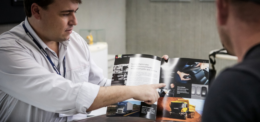 A man is reading a magazine that showcases a truck.