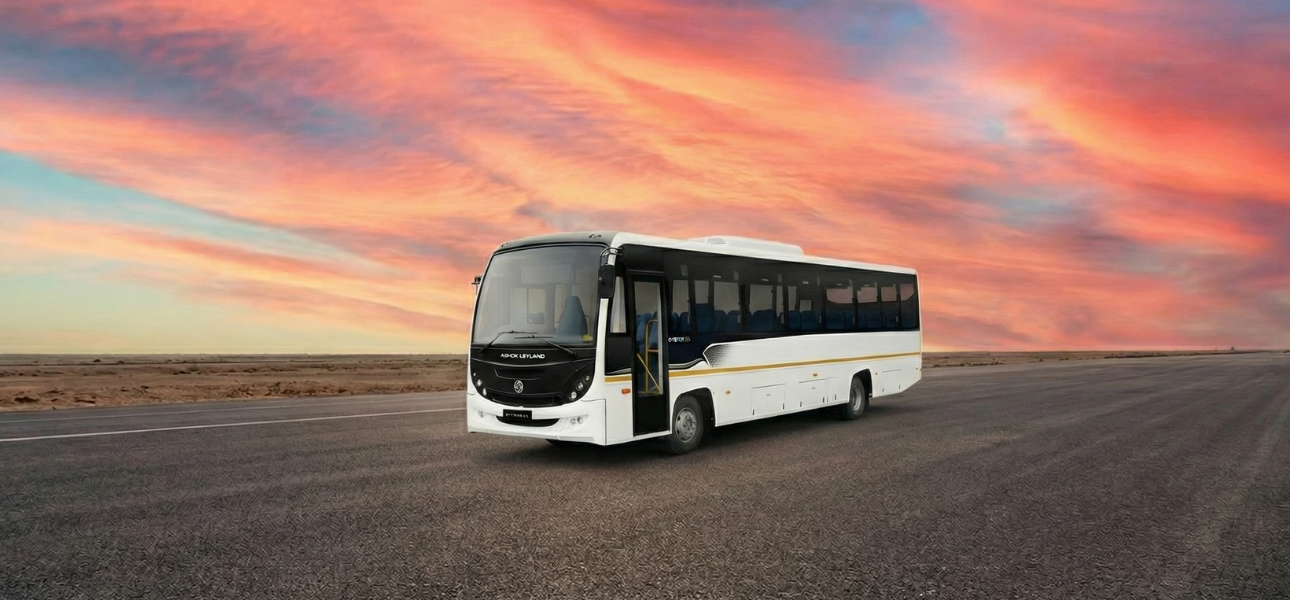 A white Ashok Leyland bus featuring bold black and white stripes on its exterior.