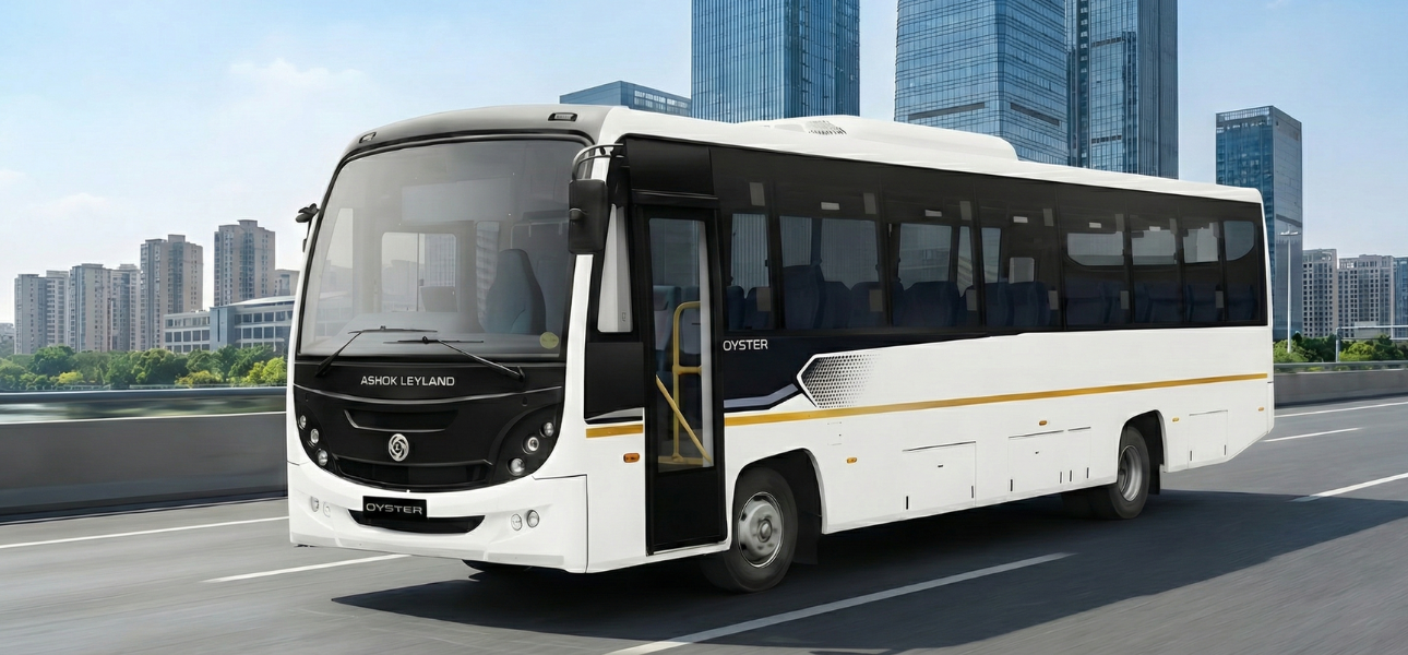 An Ashok Leyland MITR bus travels down a road with trees and mountains in the background