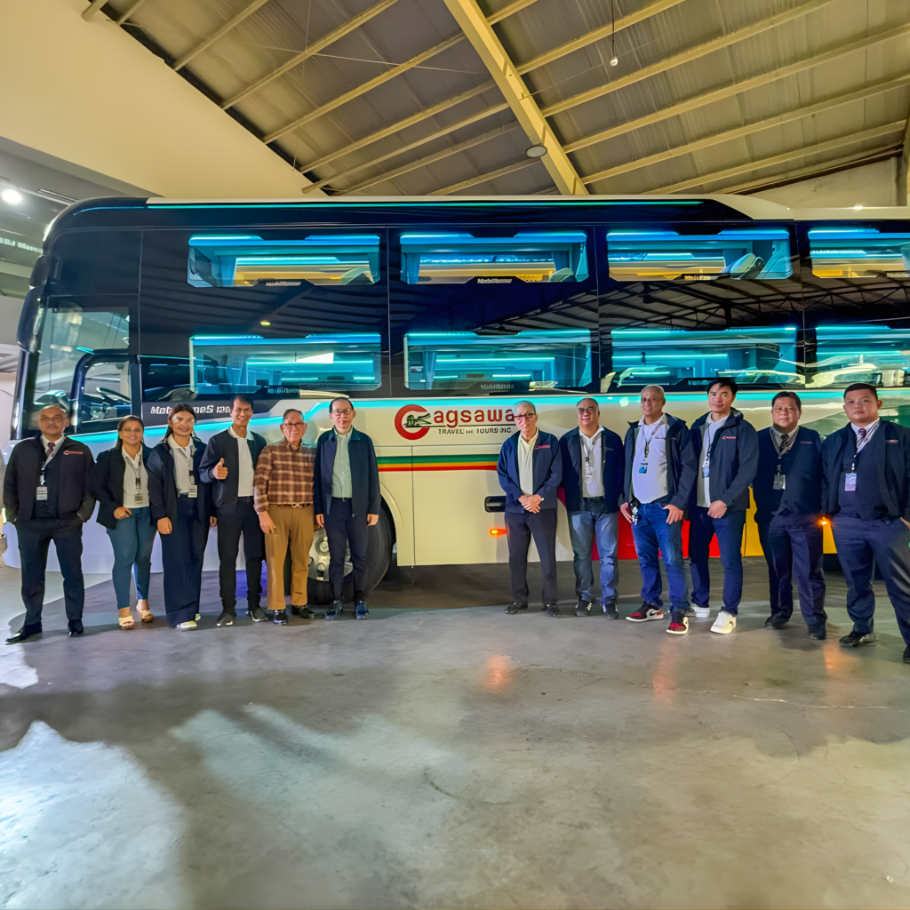 A group of people stands together in front of a bus, smiling and chatting.