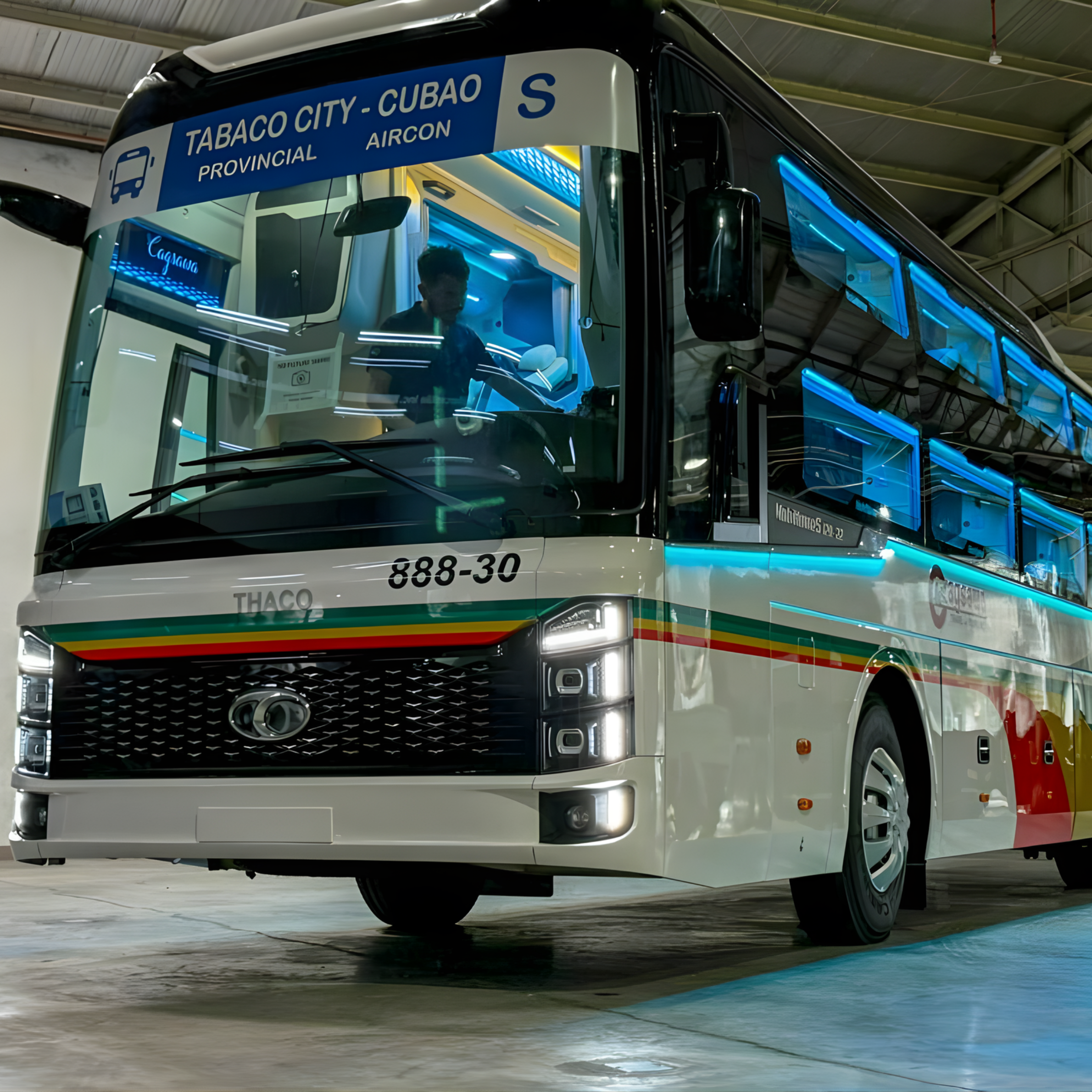 A Cagsawa bus is parked inside a garage, with a driver visible at the wheel.