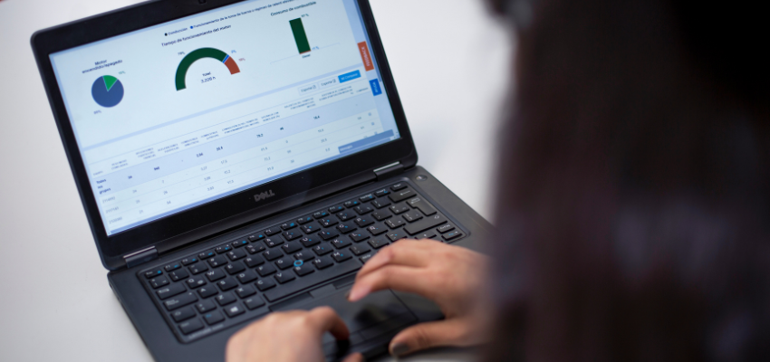 A woman working on a laptop, viewing a graph that illustrates data trends.